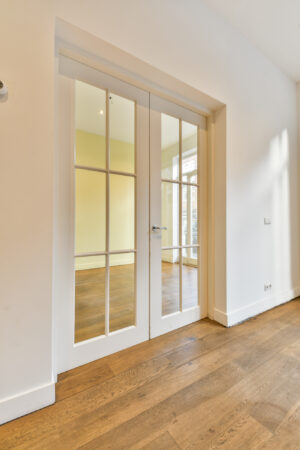 Witte dubbele glazen binnendeuren met roedeverdeling in een interieur met houten vloer in de Korte Schimmelstraat.